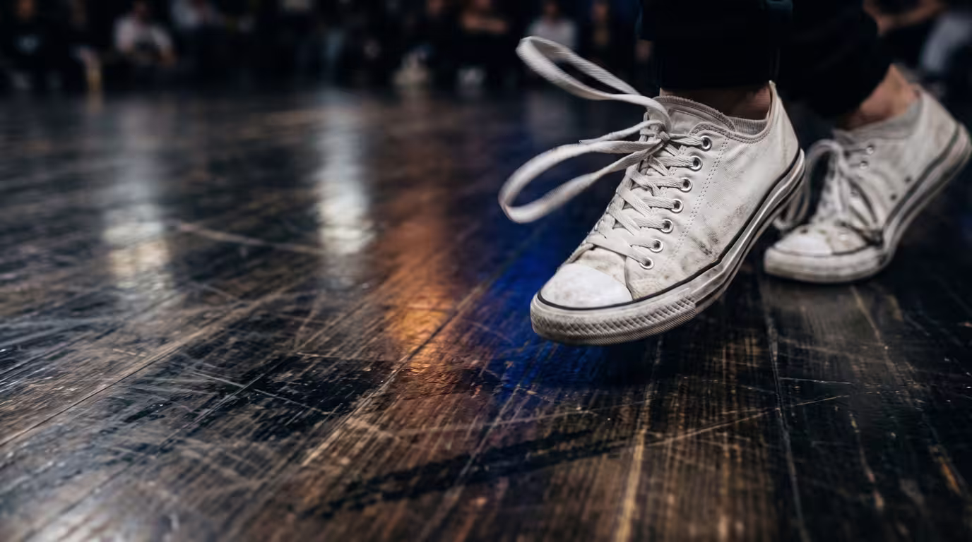 Close-up of a footwork dancer's sneakers blurred in rapid motion on a wooden floor